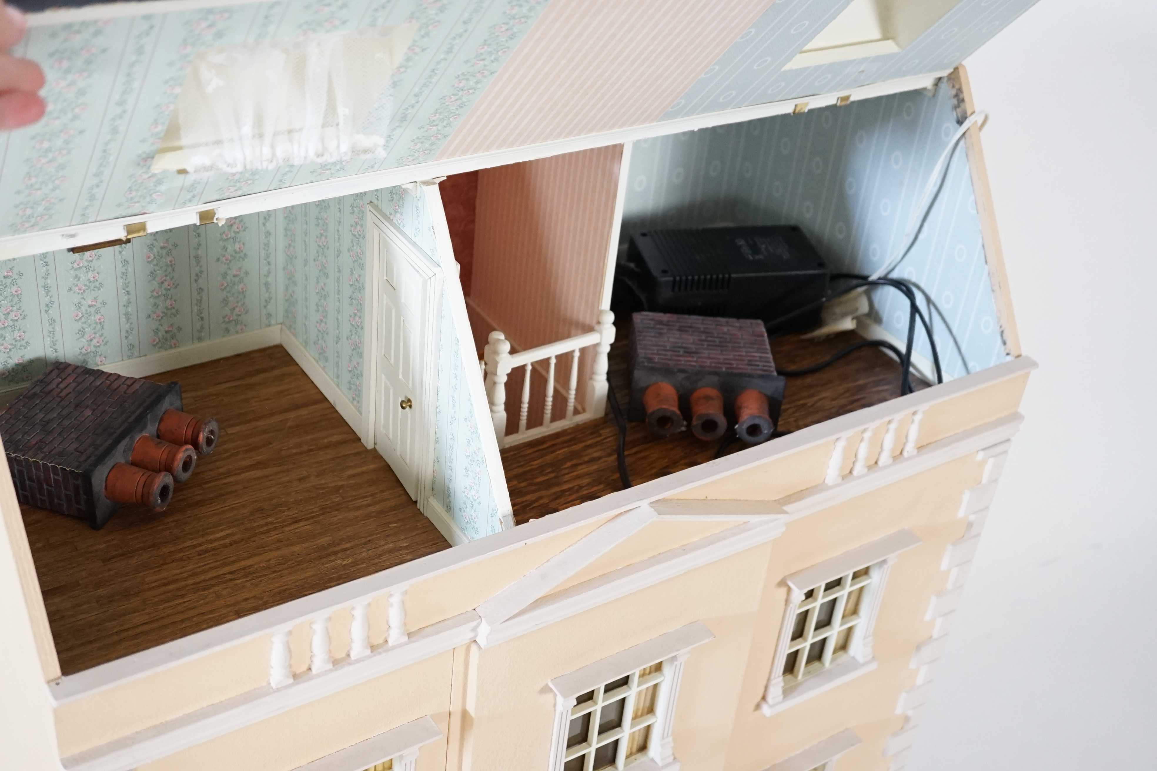 A large modern Georgian style dolls house and extensive contents, with eight fully decorated rooms on four floors, and fitted with electric lighting, removable front steps and pavement section to access basement rooms, 1